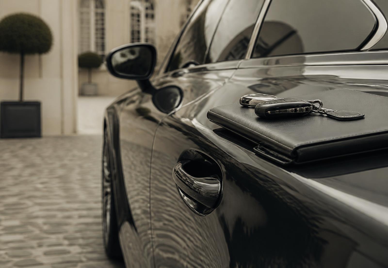 Detail of a dark luxury car with keys resting on a leather folio